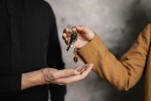 Detailed close-up of one person handing over keys to another, symbolizing a real estate transaction.